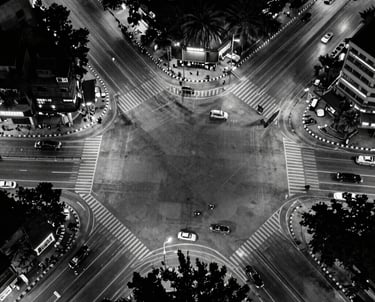 A bird's eye view of a modern Pune intersection at night, captured in high-contrast black and white, representing the urban energy of our base.