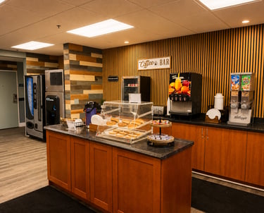 Hotel breakfast bar area featuring fresh bagels, cereal dispensers, and a coffee station.