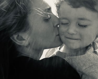 Black and white portrait of a mother kissing her toddler son on the cheek at Seventh Sky VA