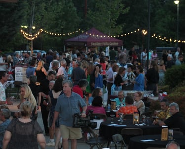 Crowd at the Paradise Chocolate Festival event with string lights and vending tables.