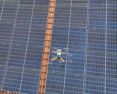 A thermal imaging drone flying over a residential rooftop solar panel array for maintenance inspection.