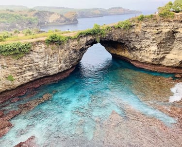 Broken Beach in Nusa Penida, Bali, featuring a natural rock arch over turquoise ocean water.