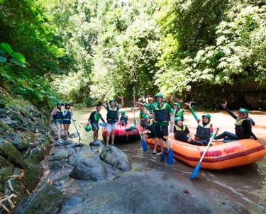 Group of tourists in life jackets and helmets enjoying white water rafting on a tropical river.