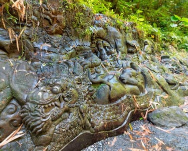 Ancient Balinese stone carvings of mythical creatures and dragons on a mossy jungle wall.