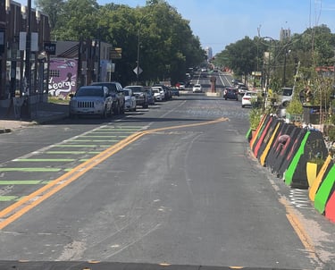 George Floyd Square parked cars, a black speed bump, and colorful traffic barriers.