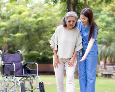 A female caregiver helping a female patient walk