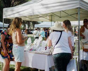 Clientes explorando exhibiciones de joyería artesanal en un mercado de artesanos al aire libre bajo 