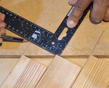 Contractor using a speed square to mark precise cuts on wood slats for custom wall panel installation