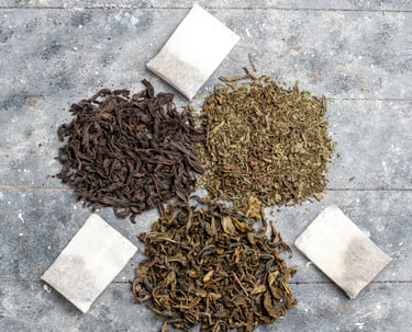Loose Hojicha tea and tea bags displayed on a grey surface.