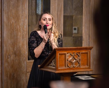 a woman in a black dress standing at a podium with a microphone