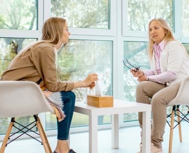 two women sitting at a table with a cup of coffee