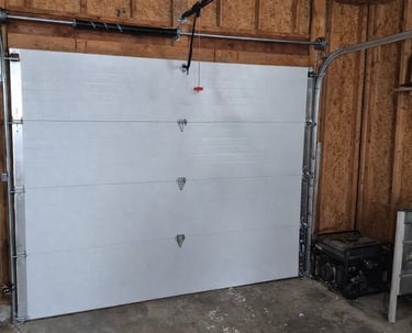 Interior view of a modern white sectional garage door installation with overhead tracks and spring system.