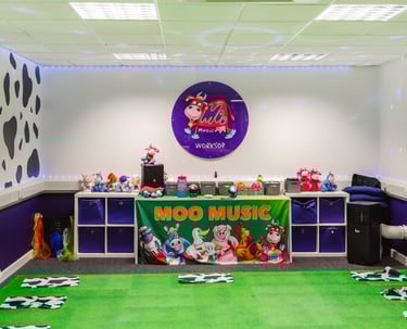 A picture of the Moo room, showing the front table, logo and bright set up of the room