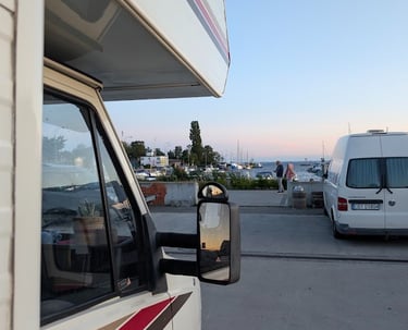 Casa Mariposa parked by the harbor at sunset with boats in the background