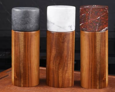 A set of three natural wood pepper mills with a marble top, available in three colours 