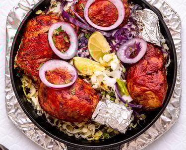 Creamy Indian butter chicken curry in a copper bowl garnished with cashews, almonds, and cream drizzle.