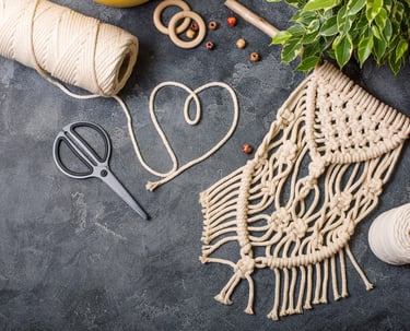 Tapiz de macramé hecho a mano con cordón de algodón, aros de madera y tijeras.