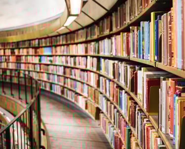 a library with a long row of bookshelves and a circular glass window