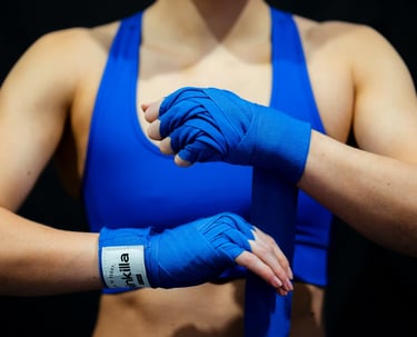Frau in blauem Sporttop beim Umwickeln ihrer Hände mit Boxbandagen – Symbol für mentales Boxen und Selbstbehauptung