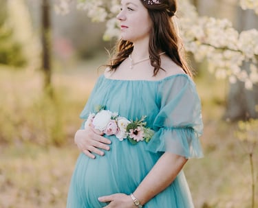 a pregnant woman in a blue dress standing in a field