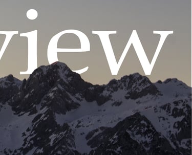 Panoramic mountain view of snow-capped peaks against a dusky twilight sky.