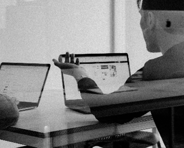 Two people with labptops talking.