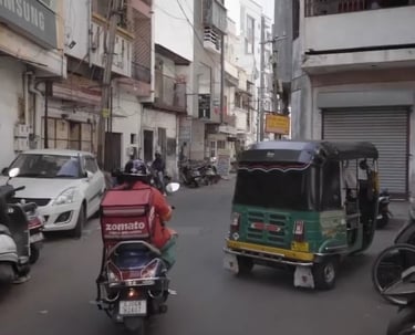 a zomato rider riding a motorcycle down an indian street