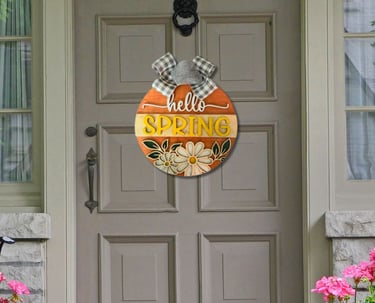 A welcoming door hanger that says "Hello Spring" hanging on a house door