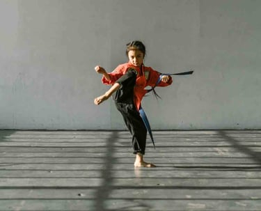 a woman in a red shirt and black pants is doing a karate pose