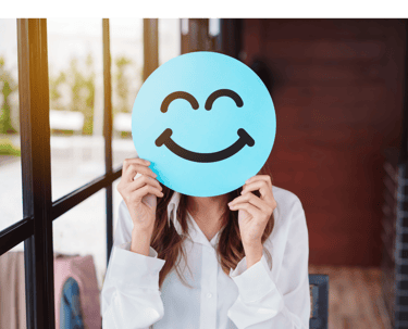 Girl covering her face with an image of a emoticon smiley face