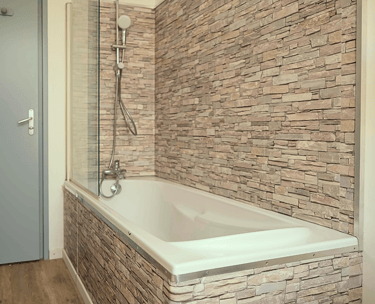 Salle de bain moderne avec baignoire et carrelage effet pierre naturelle.