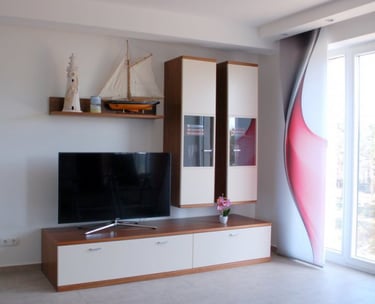Wohnwand und Flachbild-TV: Dekoriert mit Leuchtturm, Segelboot und Kerze