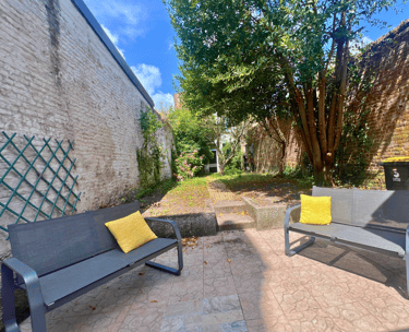 Jardin extérieur avec bancs et verdure, idéal pour se détendre en groupe.
