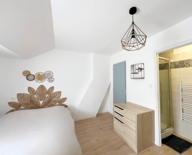 Chambre cosy avec lit double, déco murale et accès salle de bain privative.