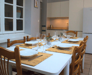 Salle à manger conviviale avec grande table dressée dans appartement équipé.