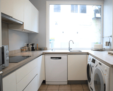 Cuisine moderne équipée avec lave-vaisselle et lave-linge pour séjour professionnel.
