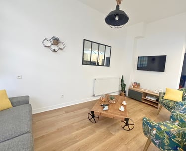 Salon moderne avec canapé, TV murale et fauteuils confortables pour détente.