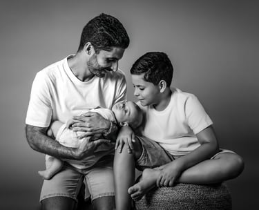 "Un retrato de familia en blanco y negro, padre con su hijo mayor y bebé en brazos"