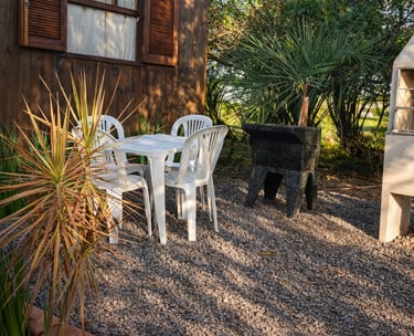 Área de lazer externa da cabana com churrasqueira, tanque e mesa.