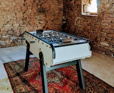 Un babyfoot posé sur un tapis oriental dans une grange en pierre