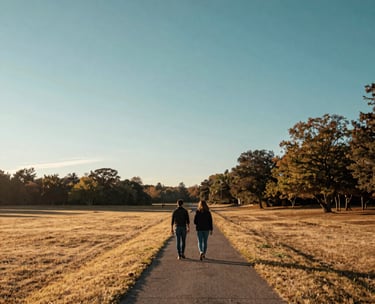 A wide-angle landscape shot of a couple walking together along a path at sunrise in a North American park, symbolizing a fresh start and shared journey. Soft morning light, palette of sandy yellow and deep teal.
