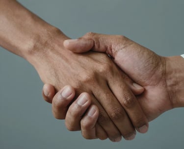A close-up of two South Asian / Indian hands joined together in a supportive gesture, soft lighting, professional and compassionate atmosphere, warm tan and gray-blue tones in the background.