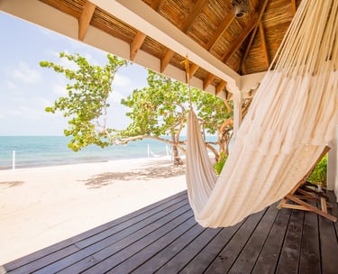 a hammock hanging from a porch over looking Belize beach