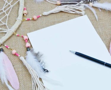 Feuille et stylo près d’un attrape-rêves, symbole d’inspiration et d’introspection selon l’esprit d’Ecl’OSons