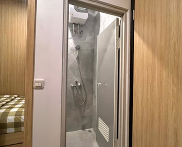 Kamar mandi dalam di Kos Si Bos Surabaya dengan shower modern, dinding keramik, fasilitas premium