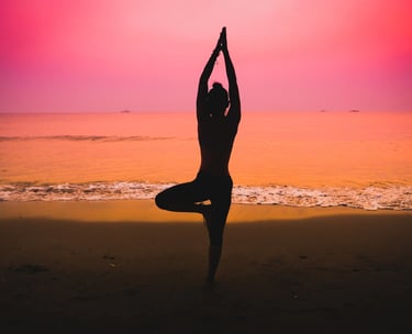 Silhouette of a woman practicing yoga on the beach at sunset