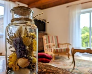 un pot de fleurs séchées dans un bocal, le salon en arrière plan