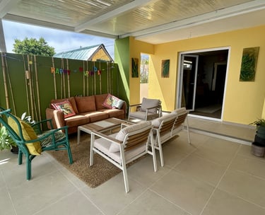 Modern outdoor patio furniture set on a covered terrace with colorful green and yellow walls.