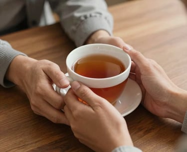 A close-up of a person's hands holding a warm cup of tea, resting on a wooden table during a therapy session, soft lighting, warm and safe atmosphere, Hispanic setting.