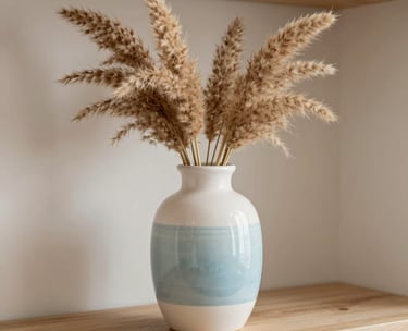 A close-up of a decorative ceramic vase with dried pampas grass on a light wooden shelf, soft natural lighting, Hispanic interior design style, colors of white and pale blue.